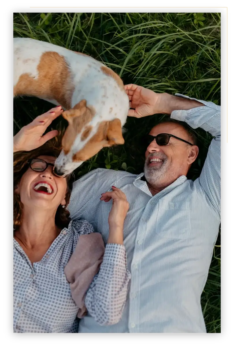 Couple laying with dog in grass