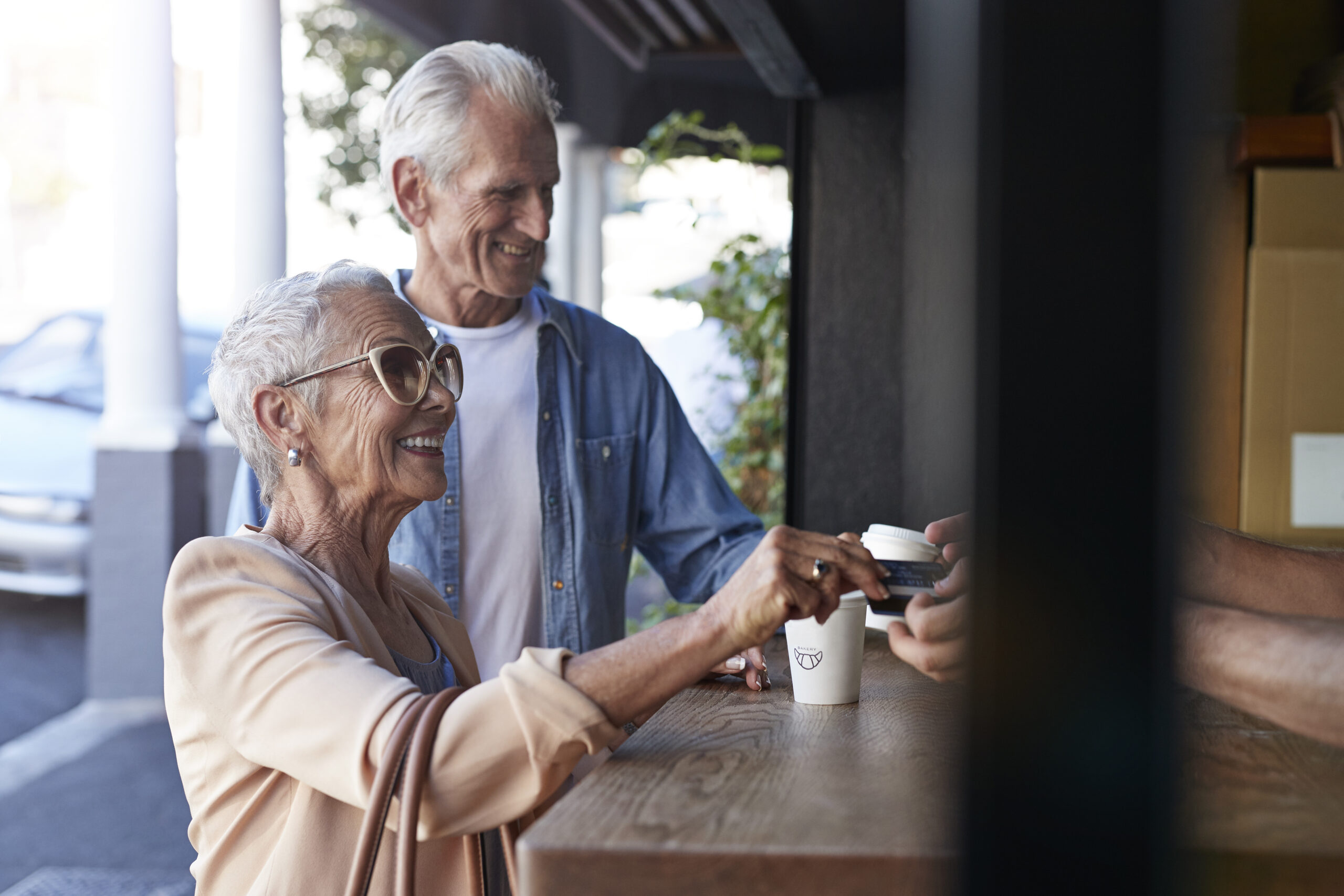 Senior couple ordering coffee to-go, at street bakery Mature couple on the move. On city break holiday